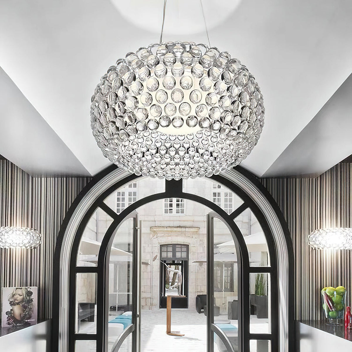 A large clear sphere pendant hangs in front of an arched black-framed doorway, with a smaller one at each side, from Clérachic.