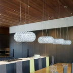 Four clear sphere pendants of falling sizes hang in a row beneath a timber ceiling over a white kitchen island, from Clérachic.