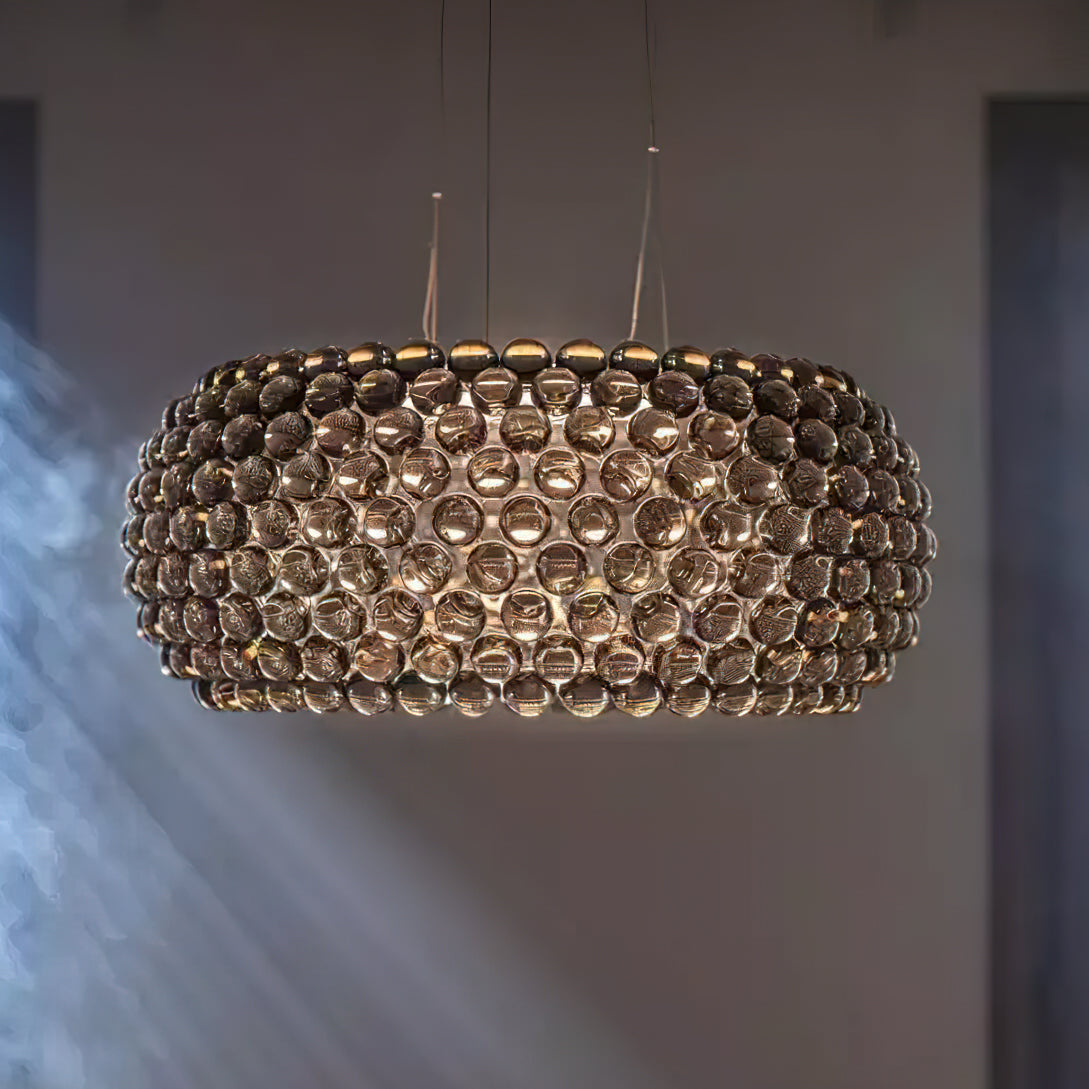 A large sphere pendant lit from within hangs against a grey wall, with soft shafts of light across it, from Clérachic.