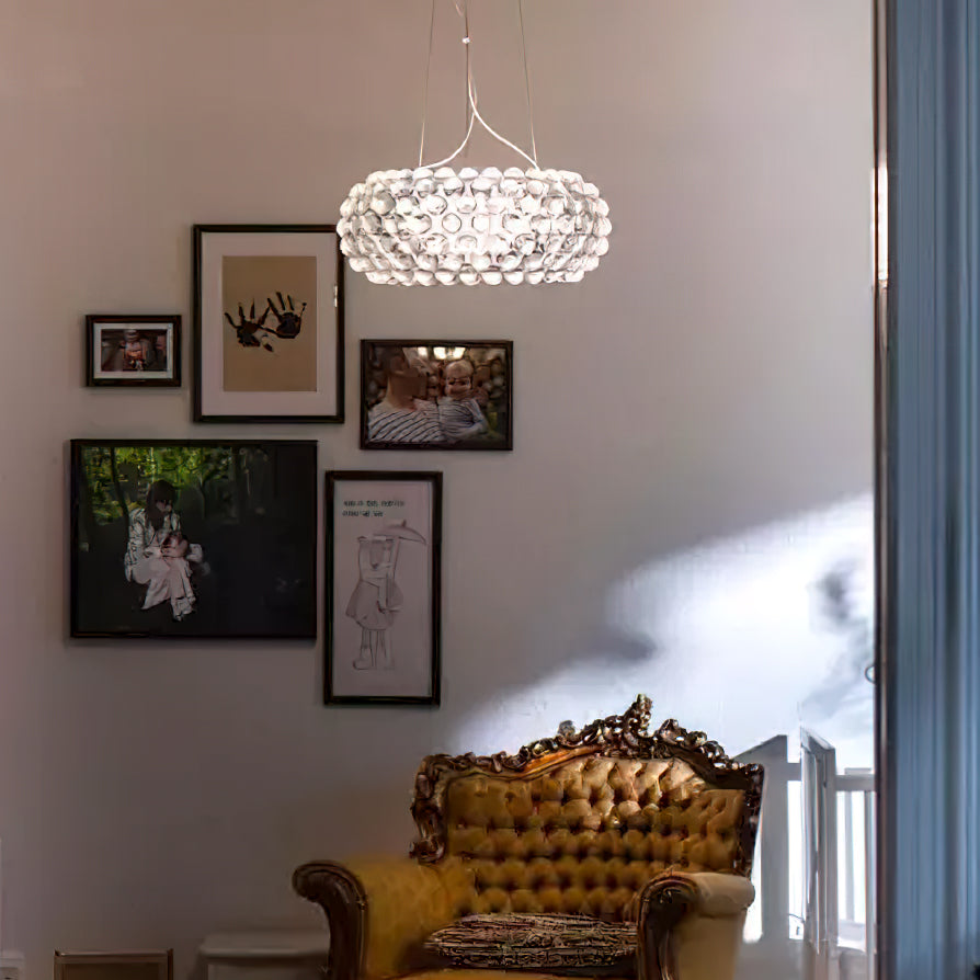 A clear sphere pendant glows above a gallery wall of framed photographs and a gilt velvet armchair, from Clérachic.