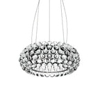 A clear sphere dome pendant seen from slightly below hangs from three fine cables against a white backdrop, from Clérachic.