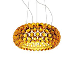 A gold-amber sphere pendant glows with warm light inside, hanging from four fine cables against a white backdrop, from Clérachic.
