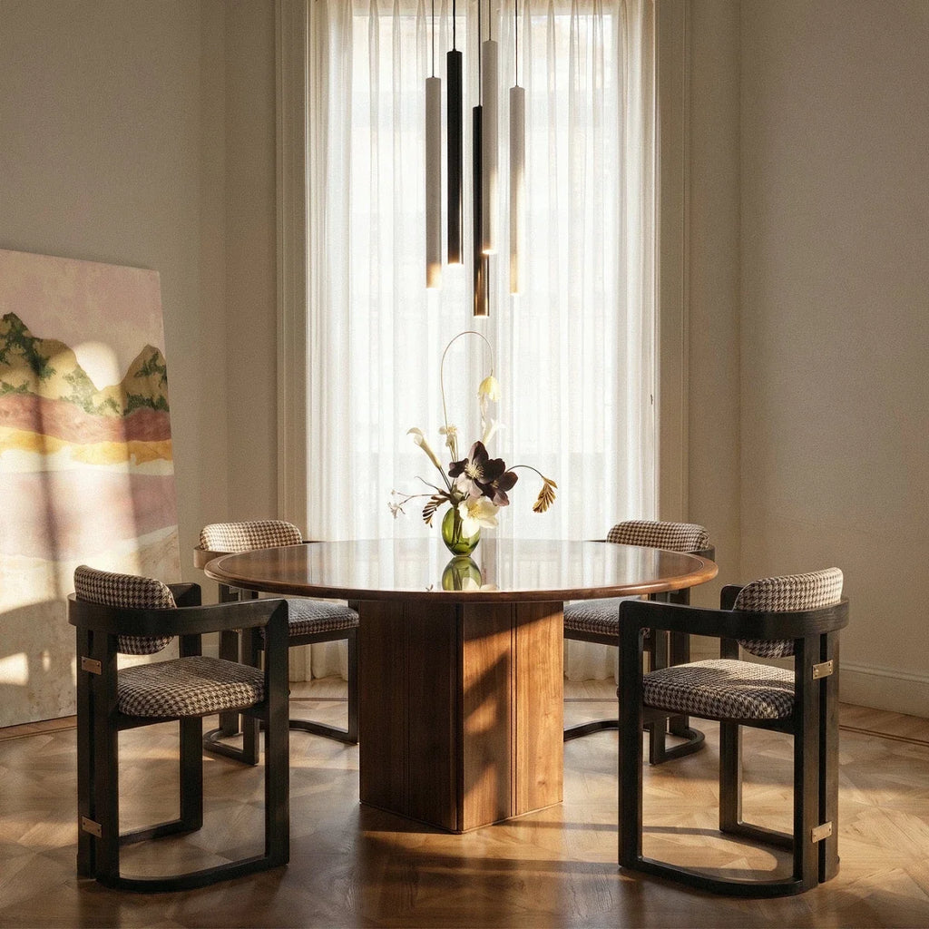 Clérachic cluster pendant light grouped in black, white and gold finishes above a round dining table by a sheer curtain.