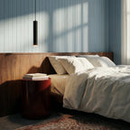 Clérachic cluster pendant light in matte black hangs bedside over a red nightstand against a blue panelled wall.