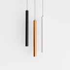Clérachic cluster pendant light group in black, gold and white cylinders hanging evenly spaced on a white ground.