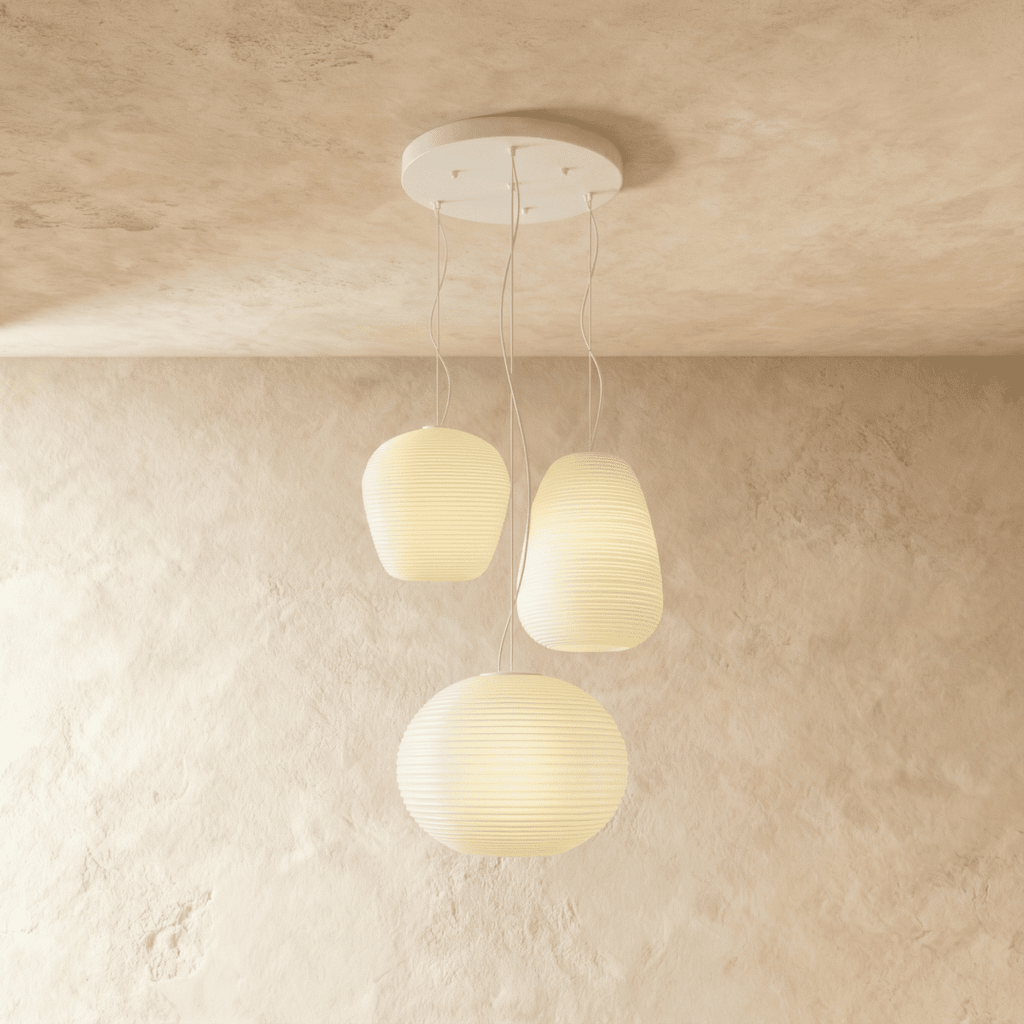 Clérachic cluster of three ribbed opal glass pendants in different shapes on one round white canopy, softly lit against limewash.