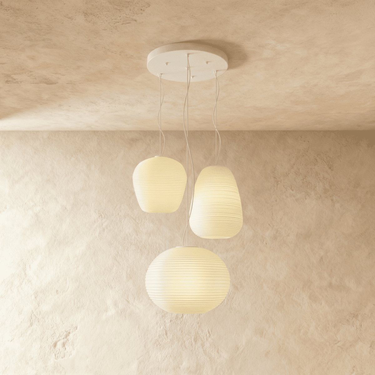 Clérachic cluster of three ribbed opal glass pendants in different shapes on one round white canopy, softly lit against limewash.