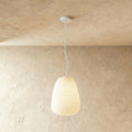 Clérachic tall egg-shaped ribbed opal glass pendant glowing softly on a thin white cord from a small white canopy.