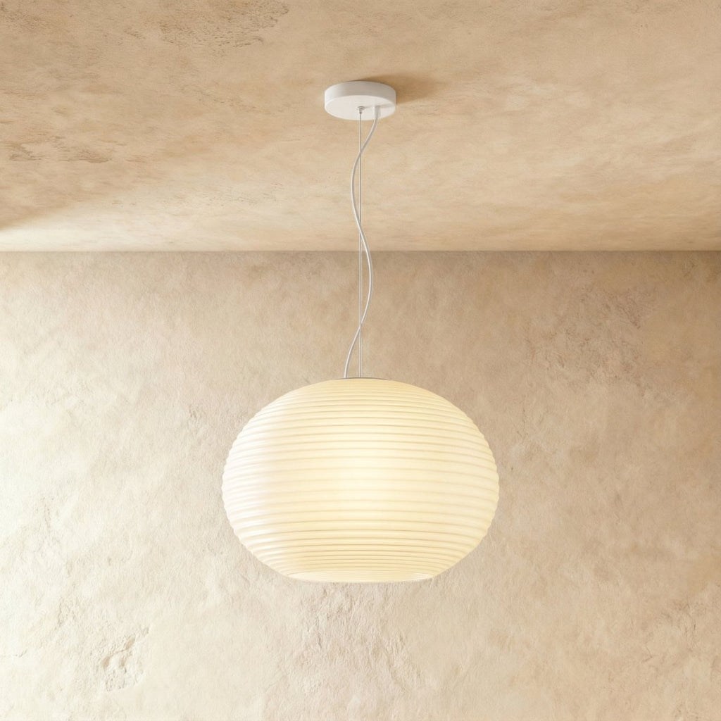 Clérachic wide oval ribbed opal glass pendant glowing softly on a slim white cord and canopy against a limewash wall.