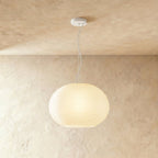 Clérachic wide oval ribbed opal glass pendant glowing softly on a slim white cord and canopy against a limewash wall.