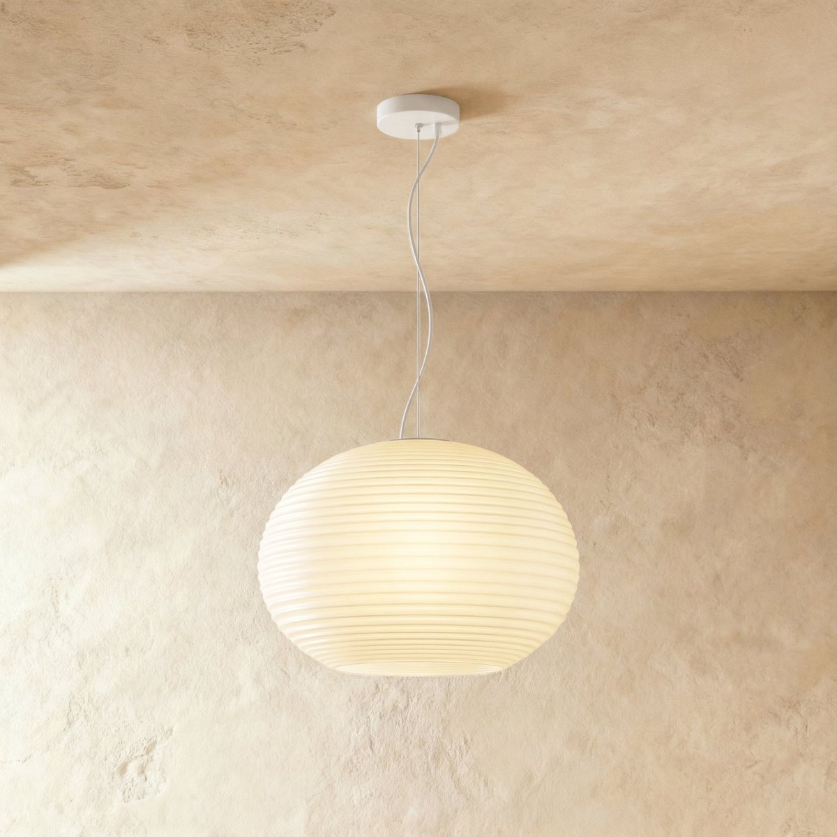 Clérachic wide oval ribbed opal glass pendant glowing softly on a slim white cord and canopy against a limewash wall.