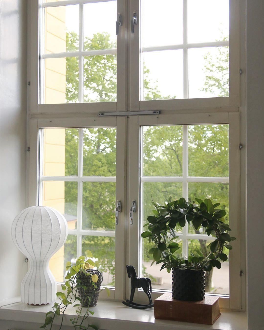Clérachic lamp on a deep window ledge, beside a green wreath, a small wooden horse and a potted plant.