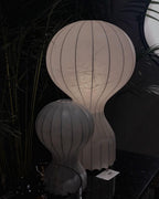 Two sizes of the Clérachic lamp in a dim showroom with palms behind, a small price tag at the foot of the larger lamp.