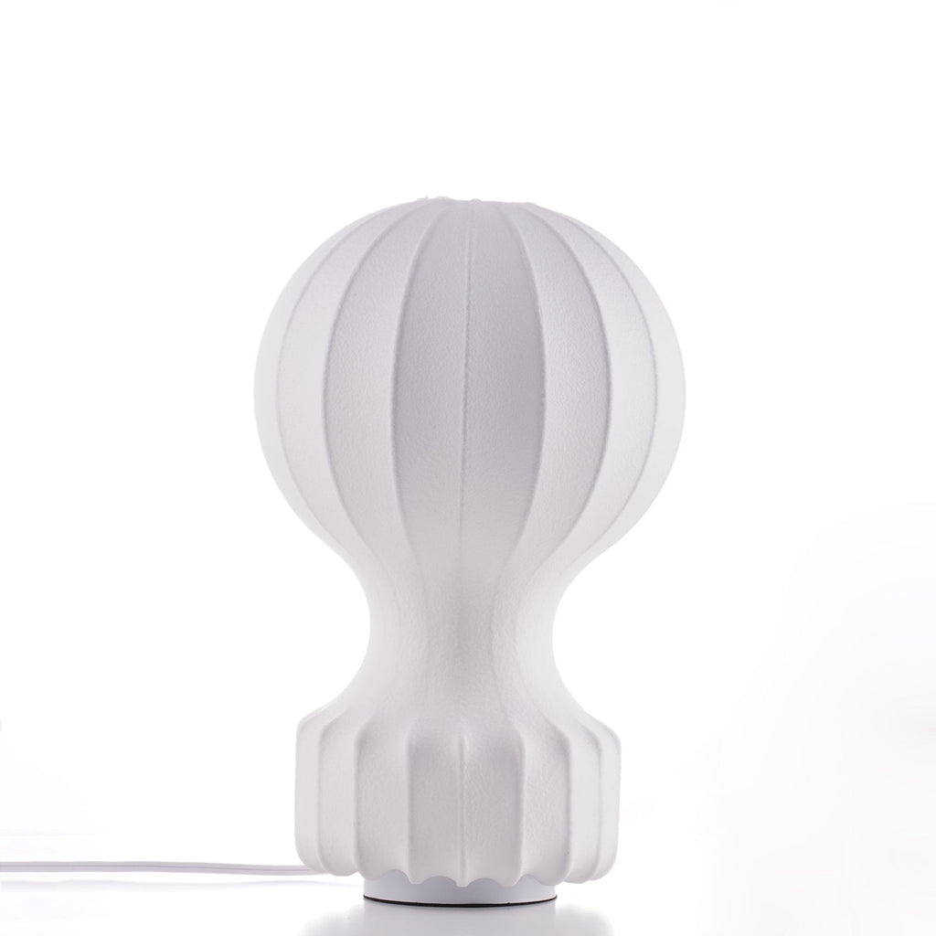 The Clérachic table lamp on a white surface, showing its pleated white shade and ribbed base, with a white cord at the foot.