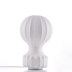 The Clérachic table lamp on a white surface, showing its pleated white shade and ribbed base, with a white cord at the foot.
