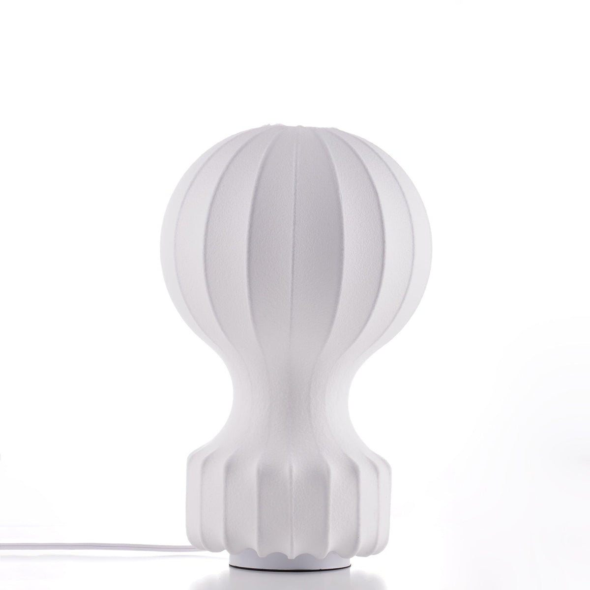 The Clérachic table lamp on a white surface, showing its pleated white shade and ribbed base, with a white cord at the foot.