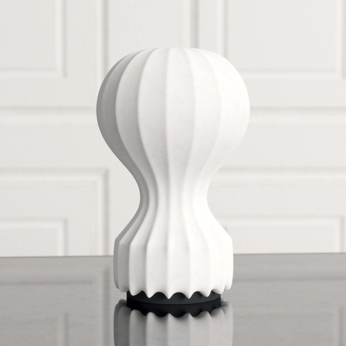 Close front view of a Clérachic table lamp, showing its ribbed white shade and the black scalloped base on a grey surface.