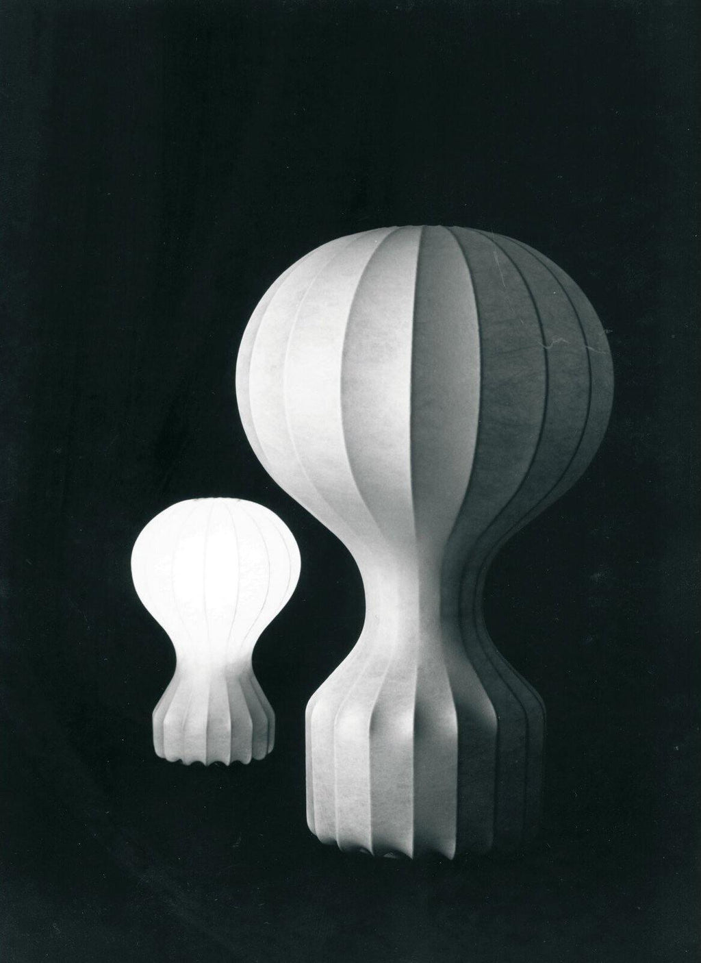 Black and white archive-style photo of two sizes of this Clérachic lamp, the small one lit and the large one beside it in shadow.