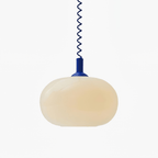 Clérachic pendant light with a milky glass shade, a blue cap and a blue stretch-coil cable, shown on a plain white backdrop.