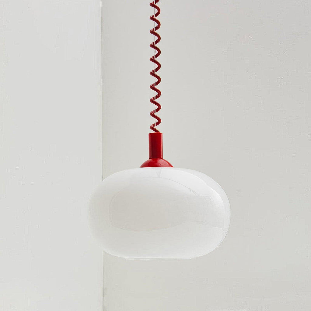 A Clérachic pendant with a red cap and red coil cable, its white glass shade unlit, hanging in a pale room corner.