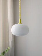 Yellow-capped Clérachic pendant with a yellow and white checked cable, its white glass shade beside a linen curtain and a trailing plant.