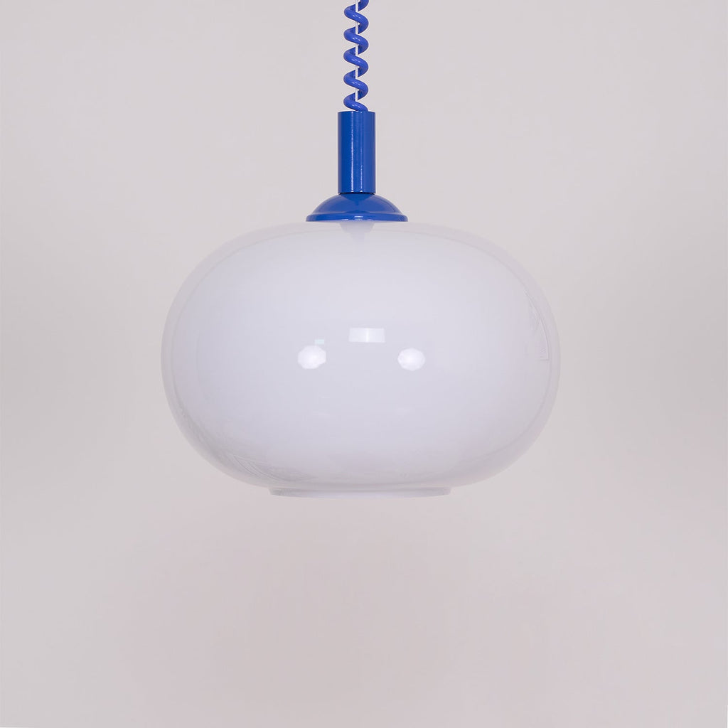 Close view of this Clérachic pendant, with a blue cap and cable, the white shade unlit and showing soft reflections.