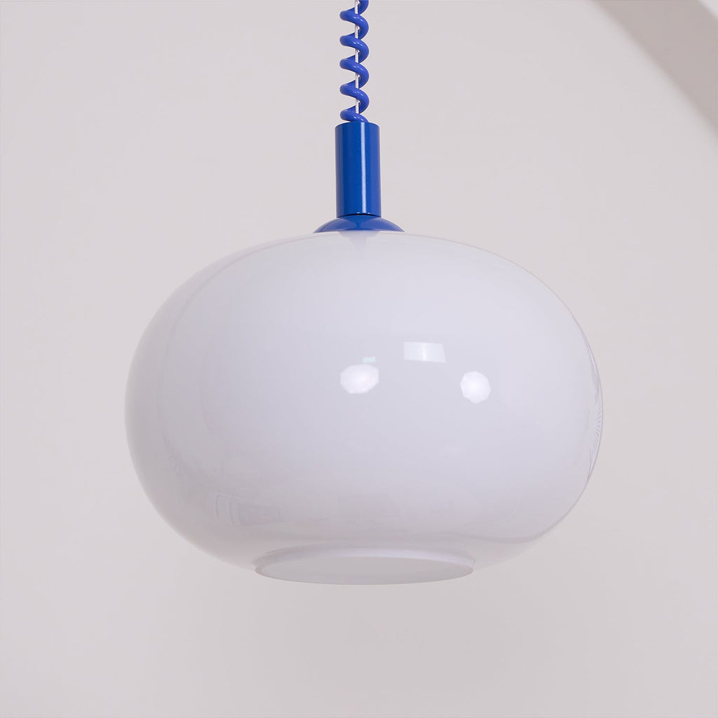 Large close view of the unlit white glass shade on this Clérachic pendant, with a blue cap and coil cable above it.
