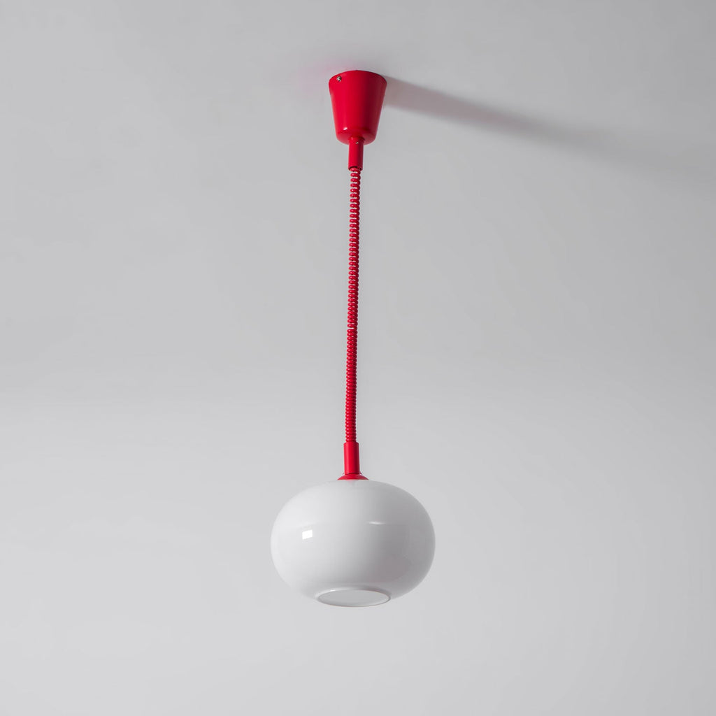 A Clérachic pendant with a red ceiling cap and straight red cable, its white shade hanging below with the opening visible.
