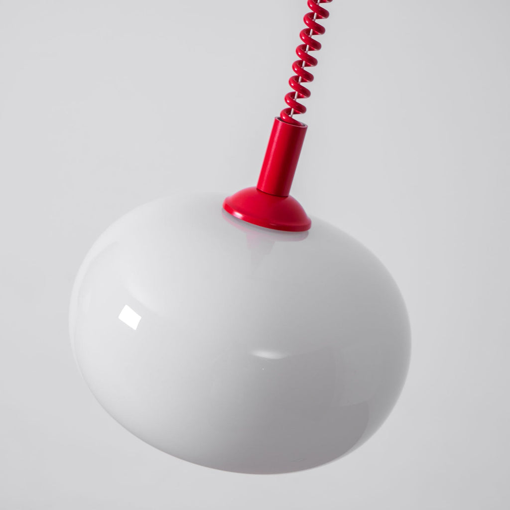 Close view of the white glass shade and red cap on this Clérachic pendant, seen from slightly below.