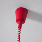 Close view of the red ceiling cap and the start of the red coil cable on this Clérachic pendant, against a grey ceiling.