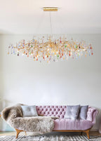 Clérachic raindrop chandelier lit above a pink tufted sofa with a fur throw and grey cushions.