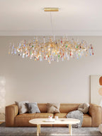 The Clérachic raindrop chandelier lit in a beige living room above a tan leather sofa.