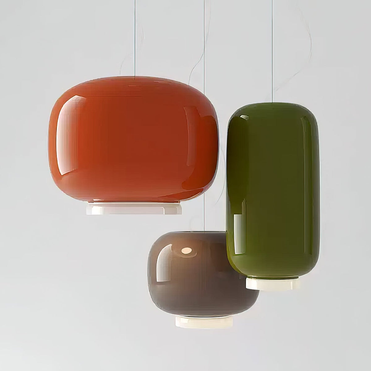Orange, olive-green and dark taupe glass shades from Clérachic hung together against a pale grey backdrop.