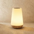 Clérachic's table lamp in its tapered silhouette, a frosted shade glowing warm above a light wood base.