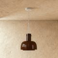 Clérachic glossy coffee-brown glass pendant with a lobed shade, hung from a slim white stem on a plaster wall.