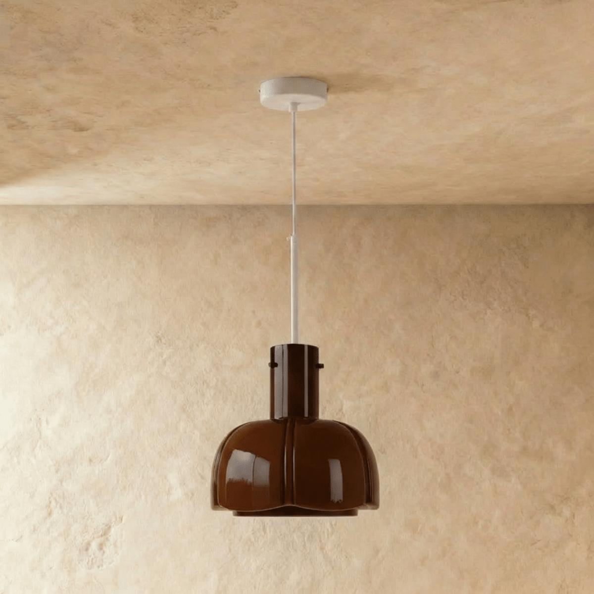 Clérachic glossy coffee-brown glass pendant with a lobed shade, hung from a slim white stem on a plaster wall.