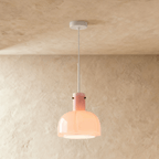 Clérachic soft pink glass pendant with a lobed shade lit from within, suspended from a white stem and ceiling canopy.
