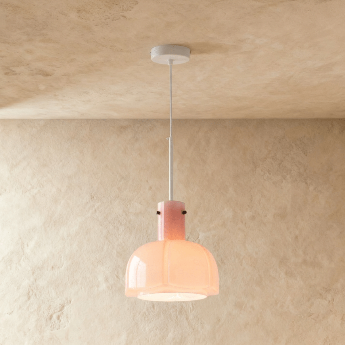 Clérachic soft pink glass pendant with a lobed shade lit from within, suspended from a white stem and ceiling canopy.