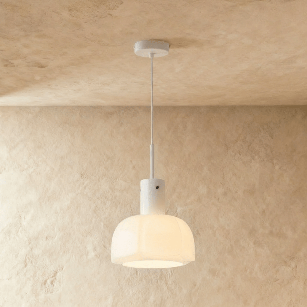 Clérachic creamy opal glass pendant with a lobed shade, glowing softly on a slim white stem against a limewashed wall.