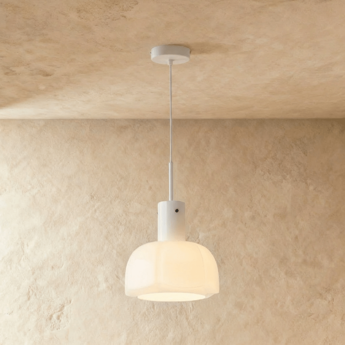 Clérachic creamy opal glass pendant with a lobed shade, glowing softly on a slim white stem against a limewashed wall.
