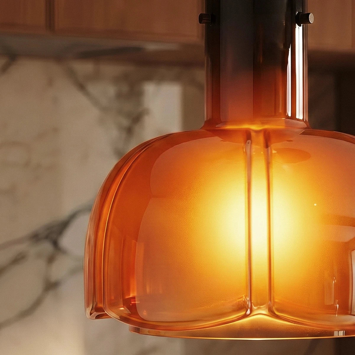 Close-up of the Clérachic amber glass pendant, its lit lobed shade fading to a darker smoked neck with metal pins.