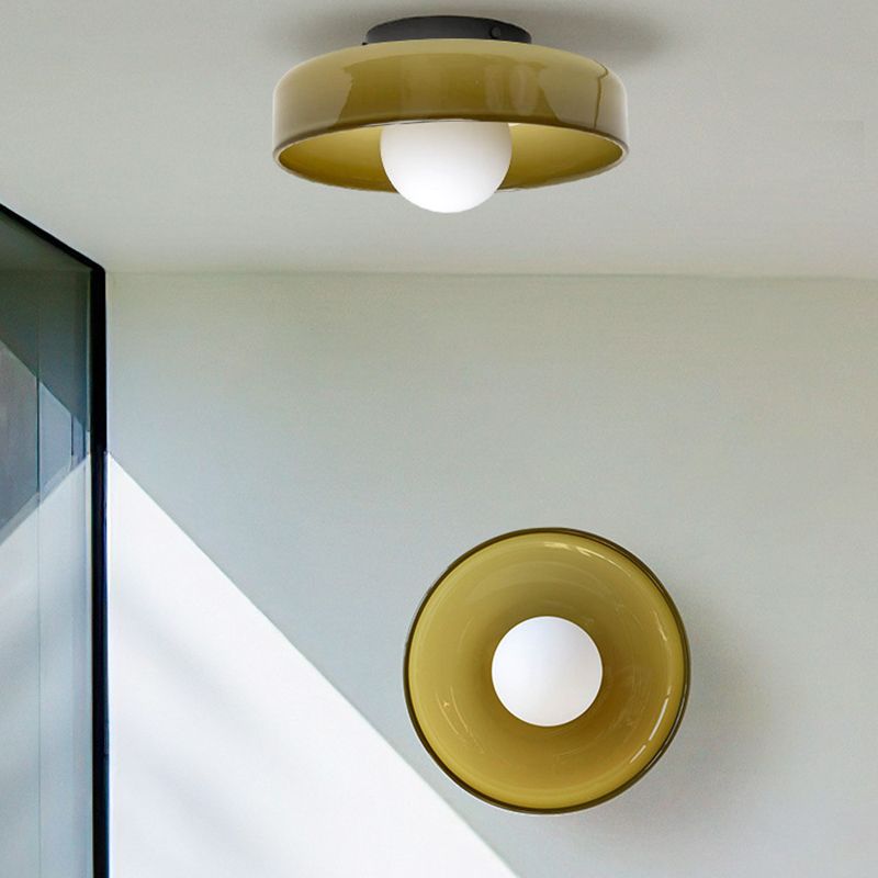 Two Clérachic coloured glass drum ceiling lights in yellow green, one flush to the ceiling and one on the wall beside a window.