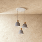 A Clérachic three-head wood disc pendant light in matte grey hangs from a round canopy against a warm plaster ceiling.