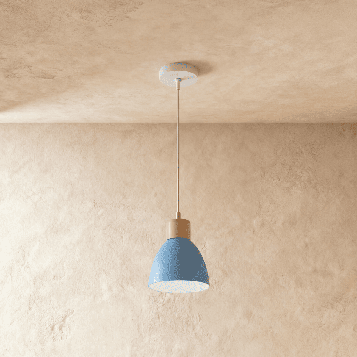 A single Clérachic wood disc pendant light in dusty blue hangs on a slim cable against a warm plaster wall.
