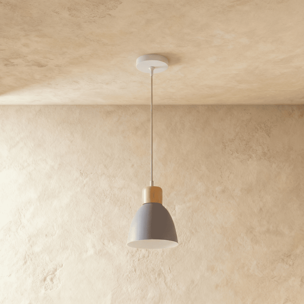 A single Clérachic wood disc pendant light in matte grey hangs on a long cable against a warm plaster backdrop.