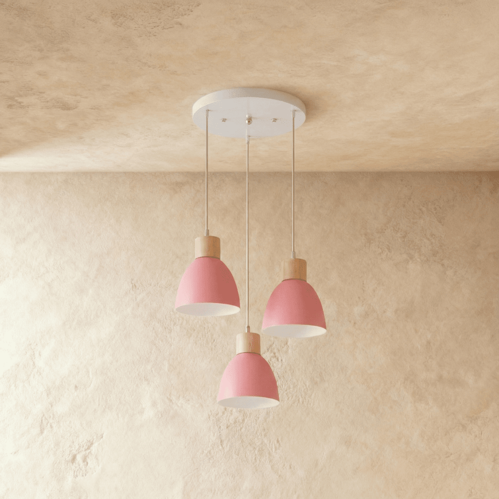 Three Clérachic wood disc pendant lights in soft pink cluster from a round canopy over a warm plaster wall.