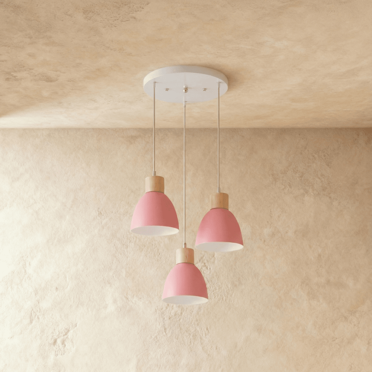 Three Clérachic wood disc pendant lights in soft pink cluster from a round canopy over a warm plaster wall.