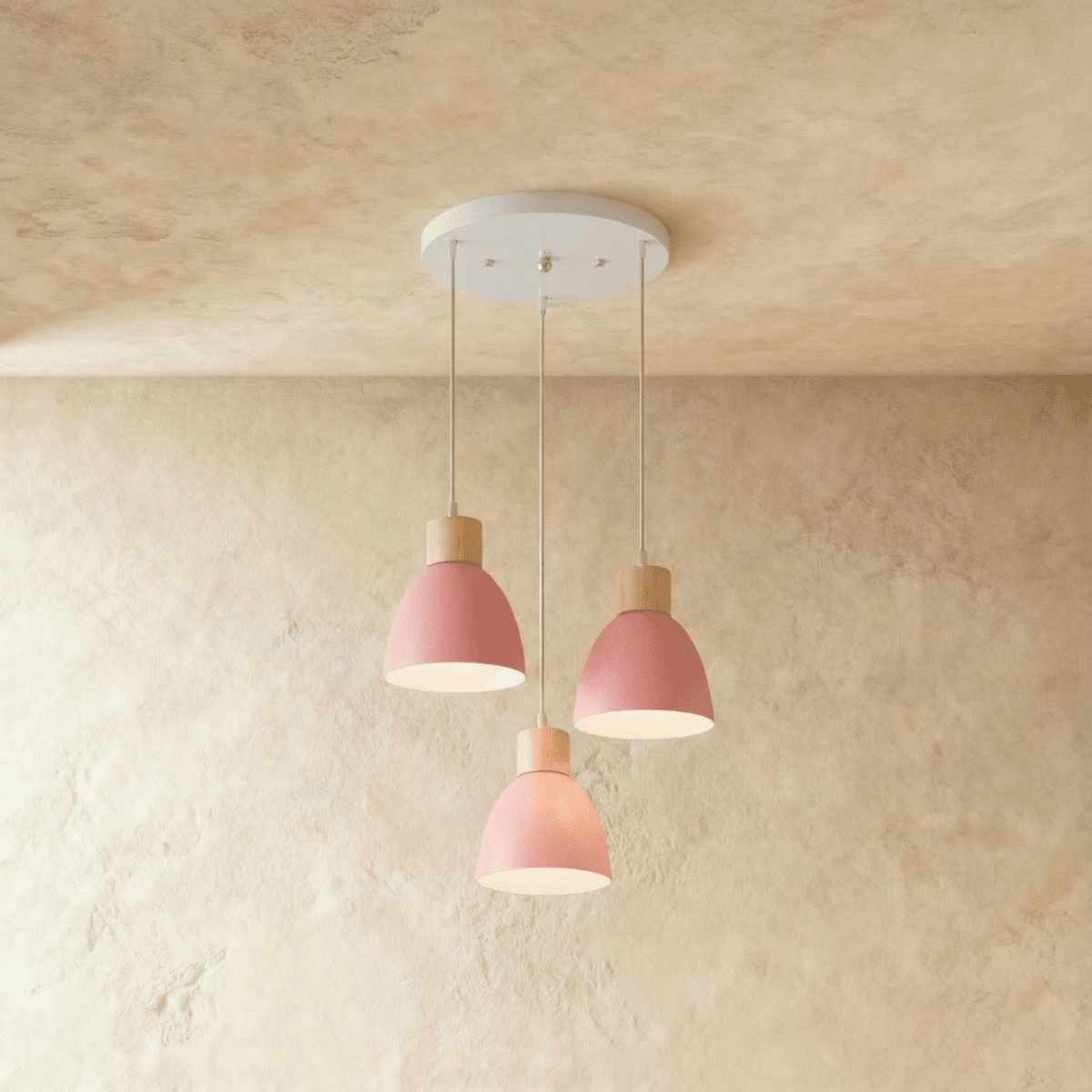 Angled view of the Clérachic three-head pink wood disc pendant light cluster hanging from its round white canopy.