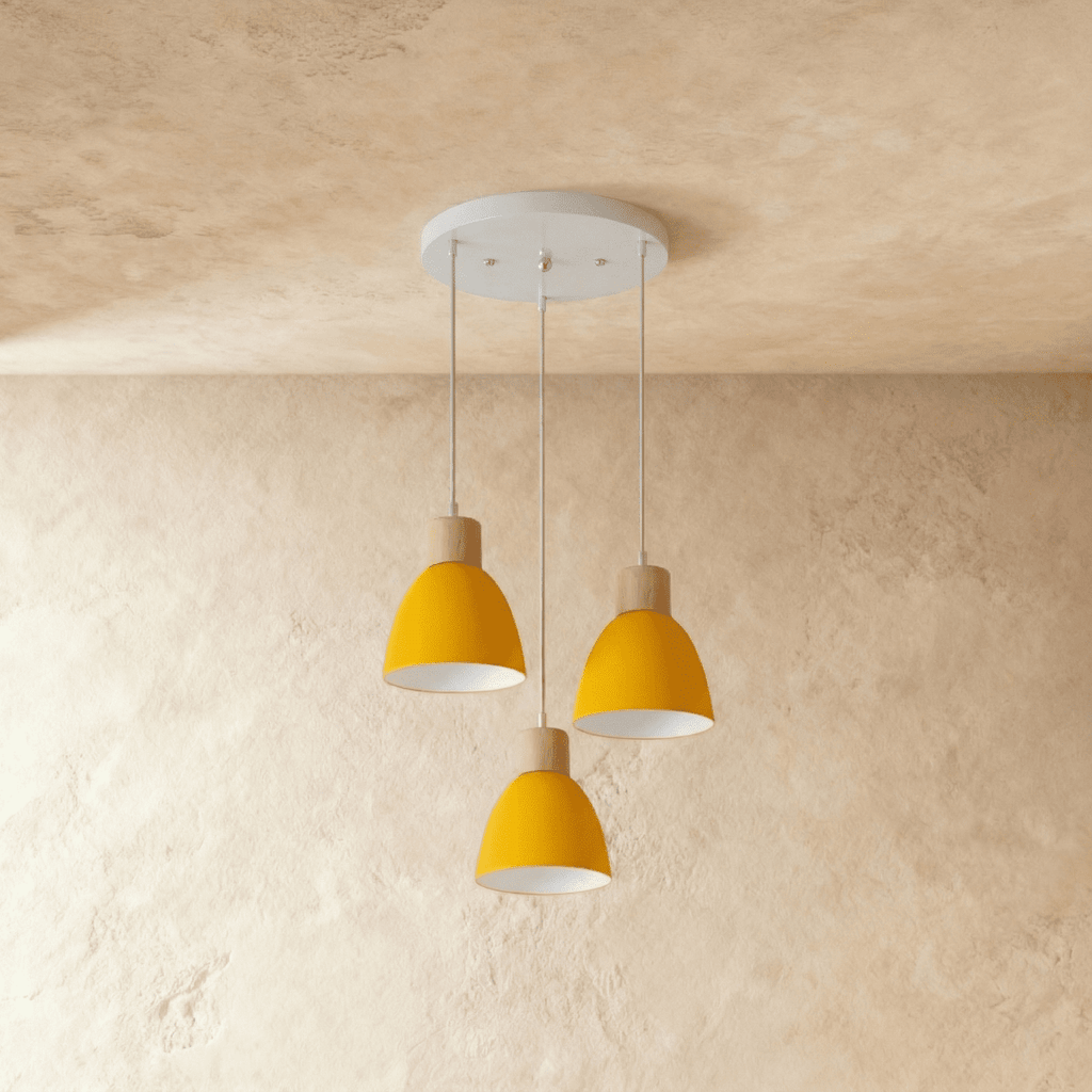Three Clérachic wood disc pendant lights in mustard yellow cluster from a round canopy against a plaster wall.