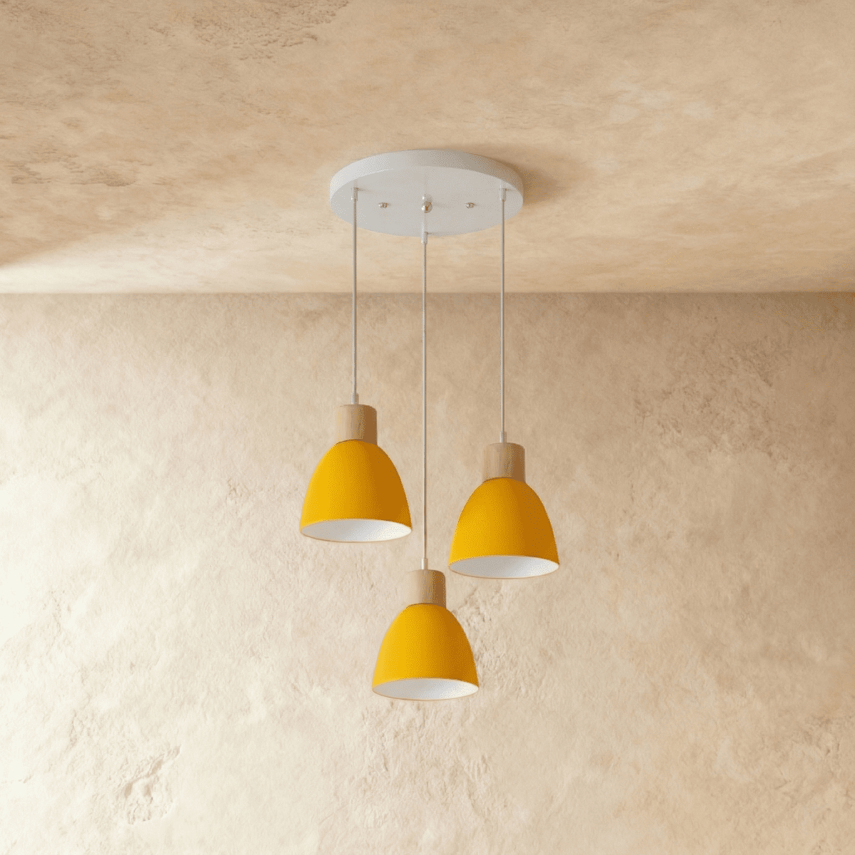 Three Clérachic wood disc pendant lights in mustard yellow cluster from a round canopy against a plaster wall.